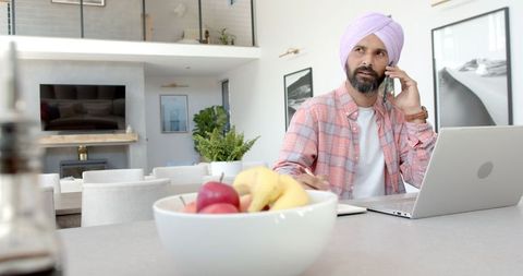 Man in Modern Home Office Talking on Phone Using Laptop