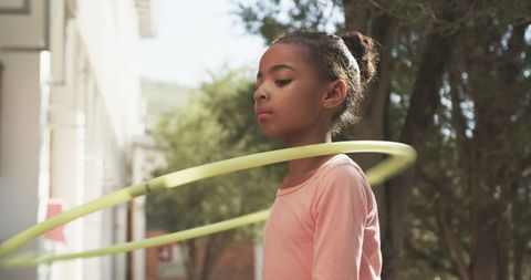 Child playing with hula hoop outdoors in sunny environment