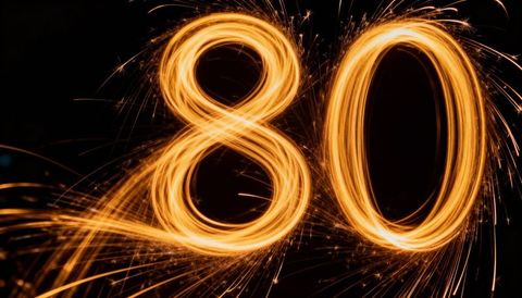 Forming golden sparkler light trails creating number 80 for anniversary celebration