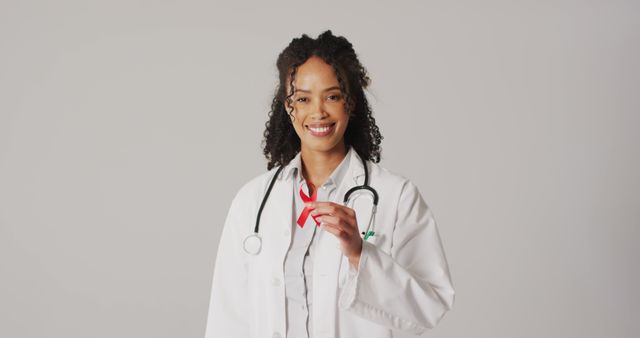 Image of smiling biracial female doctor holding orange kidney cancer ribbon. global medicine and healthcare concept.