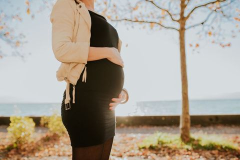Pregnant woman embracing sunshine by waterfront
