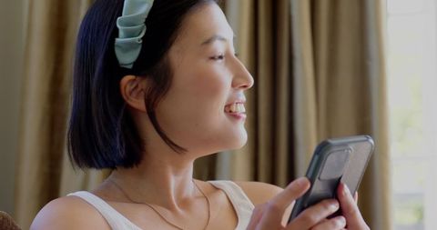 Smiling Woman Using Smartphone for Leisure Indoors