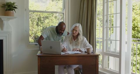 Couple planning wedding together at home with laptop