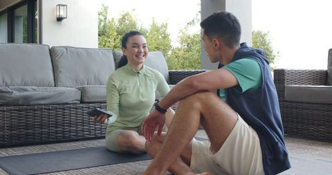 Couple Relaxing Outdoors Post-Workout with Smartphone