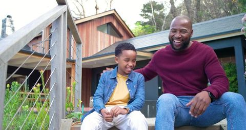 African american father and son laughing on porch steps sharing joyful outdoor family bonding