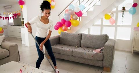 Woman Cleaning Living Room After Party Celebration