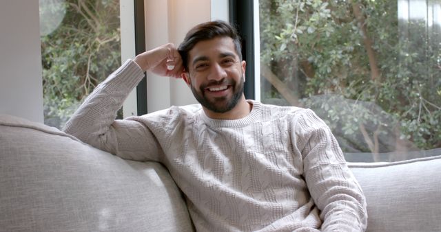 Smiling man relaxing on cozy couch near window at home - Download Free Stock Images Pikwizard.com