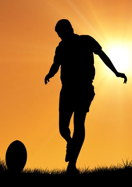 Rugby player silhouetted against setting sun balancing rugby ball on grass. Suitable for sports-related content, motivation, teamwork, athleticism, outdoor sports promotions, or sunset-themed visuals.