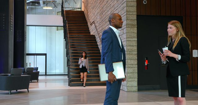 Professional businesspeople conversing in modern office lobby - Download Free Stock Images Pikwizard.com