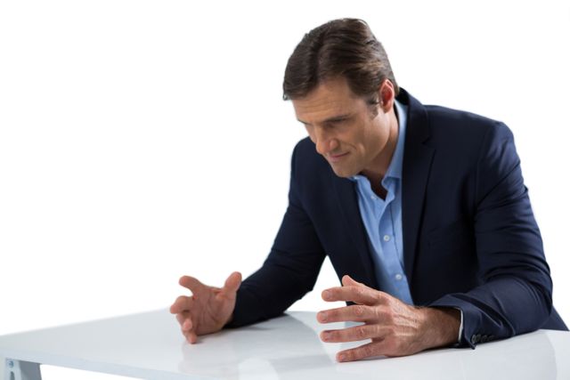 Businessman in suit sitting at desk, gesturing with hands, expressing frustration. Ideal for illustrating concepts of workplace stress, corporate challenges, business problems, and professional anxiety. Suitable for use in articles, presentations, and advertisements related to business, mental health, and stress management.