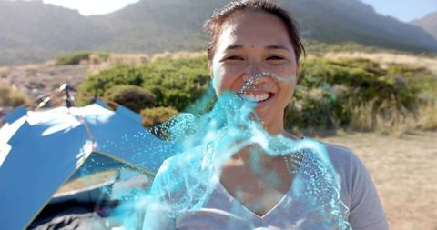 Asian Woman Smiling at Scenic Campsite with Digital Overlay
