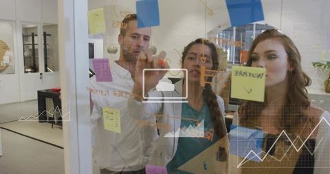Planning strategy session with diverse team writing on glass board and sticky notes