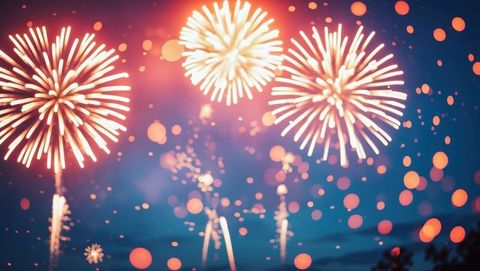 Dazzling fireworks burst under starlit sky amid glowing bokeh