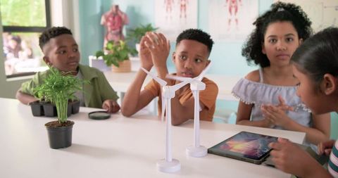 Diverse children building model wind turbines collaborating on classroom stem project