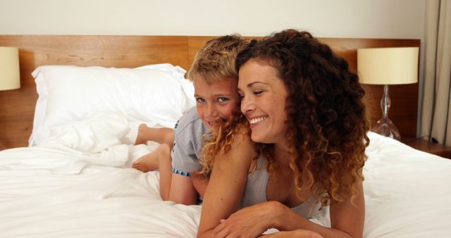 Son jumping on the bed to hug his mother at home in bedroom