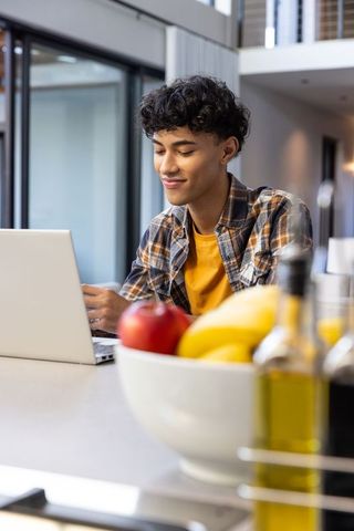 Young Man Working on Laptop in Modern Kitchen Interior