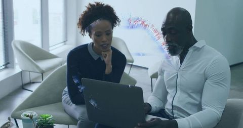 Business professionals in office lounge analyzing laptop