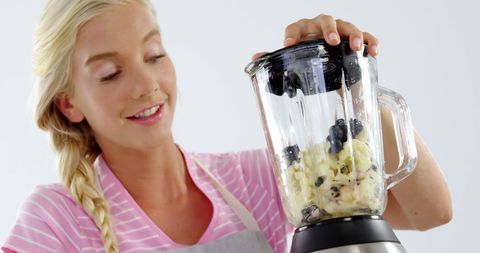 Cheerful Woman Blending Healthy Fruit Smoothie in Kitchen
