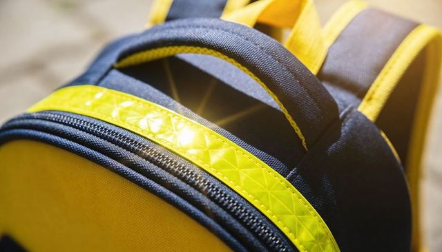 Navy backpack featuring reflective yellow safety strip, zipper detail and padded handle