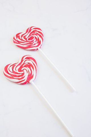 Red and white heart shaped lollipops on marble surface