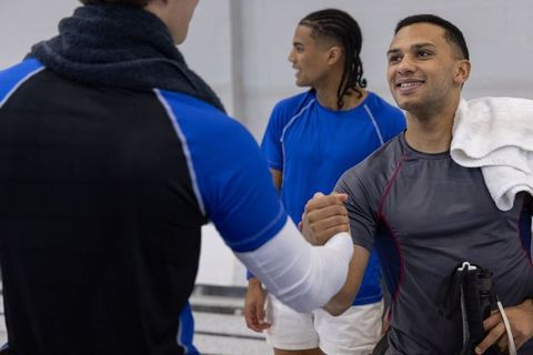 Adaptive athletes celebrating teamwork and camaraderie on indoor court with prosthetic blade