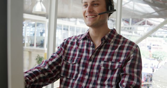 Caucasian man working as a customer service representative, with copy space. He's wearing a headset in a bright office environment, indicating a customer support setting.