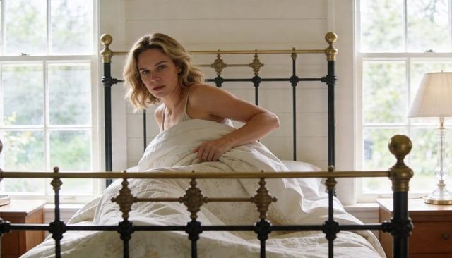 Woman Sitting Up Clutching Quilt on Vintage Metal Bedframe in Sunlit Country Bedroom