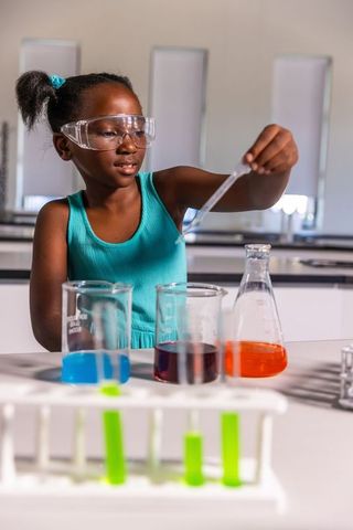 African american girl conducting colorful chemistry experiment in school laboratory