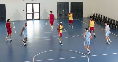 Male Athletes Competing Energetically in Indoor Basketball Game