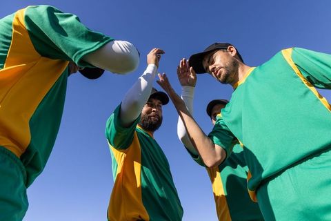Baseball teammates gathering for pregame huddle celebrating teamwork under clear blue sky