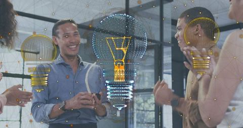 Team celebrating digital innovation around holographic lightbulb prototype in office