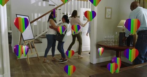 Multigenerational family welcoming guests at home, hugging in foyer with rainbow hearts