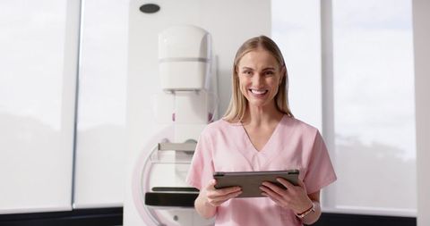 Smiling Mammography Technologist Holding Tablet in Breast Imaging Clinic