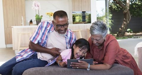 Grandparents Bonding with Granddaughter Using Tablet at Home