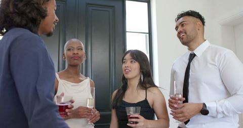 Elegant diverse guests toasting and mingling in sunlit foyer during formal cocktail reception
