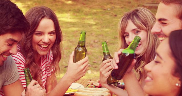 Young adults toast with beer at a cheerful, relaxed picnic outdoors. - Download Free Stock Photos Pikwizard.com