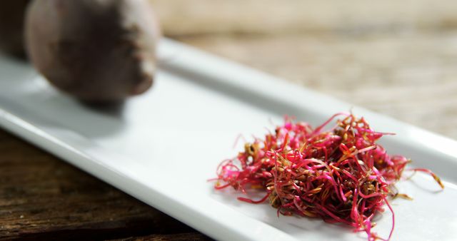 Unique close-up of red beet sprouts displayed on a white plate. Perfect for illustrating healthy eating, organic produce, and creative culinary presentations. Ideal for use in health-related blogs, recipes, or promoting vegetarian diets.