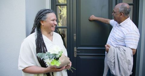 Joyful Elderly Couple Bringing Flowers to a Friend's House