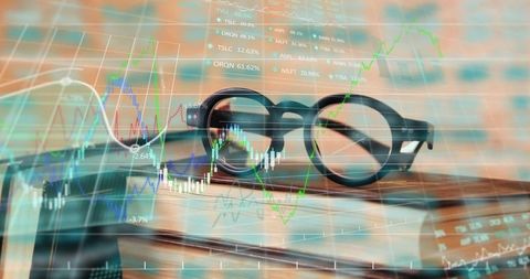 Eyeglasses on books with stock chart overlays in office setting