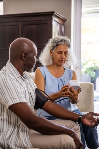 Caregiver monitoring senior’s blood pressure at home