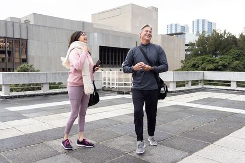 Smiling mature couple walking on urban rooftop terrace in casual activewear