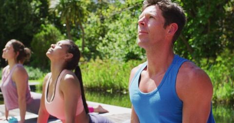 Group Practicing Outdoor Yoga in Sunny Park for Wellness