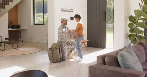 Military reunion: father in camo embraces young son indoors