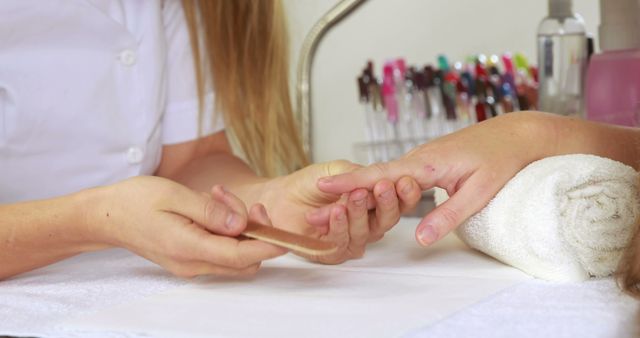 Nail technician filing customers nails at the nail salon