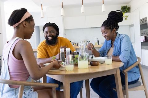 African american family enjoying healthy meal at modern kitchen table, sharing salad