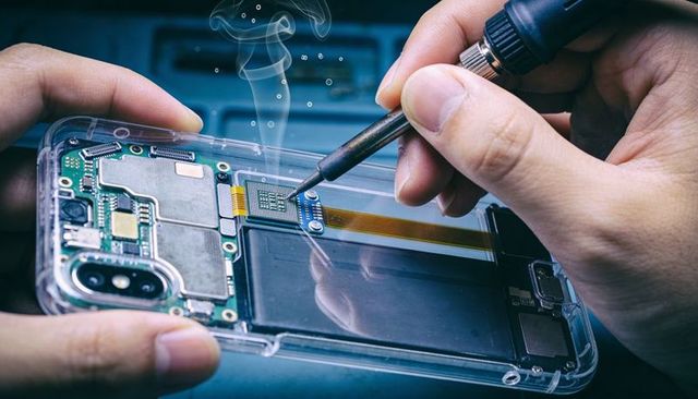 Soldering smartphone motherboard using precision iron, repairing microelectronics closeup