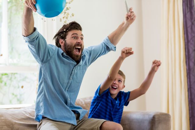 Excited father and son watching television in living room