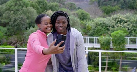 Young African American Couple Taking Selfie on Balcony Overlooking Lush Greenery, Casual Moment