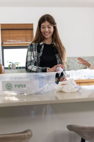 Woman sorting paper recycling at kitchen island with helper promoting sustainability