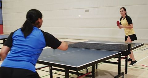 Female Athletes Competing in Table Tennis in Gym